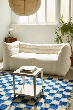 a living room with a large white couch and blue rugs on the floor next to a window