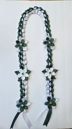 a white and green ribbon with flowers on it is hanging from the side of a wall