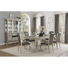 a dining room table with chairs and a china cabinet in front of the window,