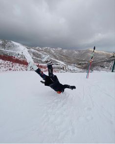 a man riding a snowboard down the side of a snow covered ski slope on a cloudy day