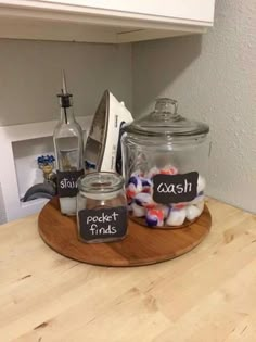 a wooden tray topped with glass jars filled with candy and other confection sitting on top of a kitchen counter