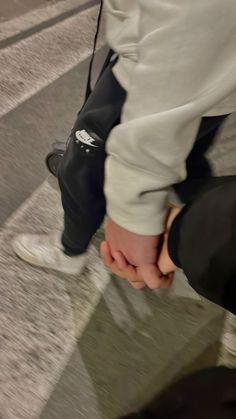 two people holding hands while walking down an airport walkway with their feet on the ground