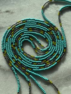 a blue and yellow beaded necklace on a white surface