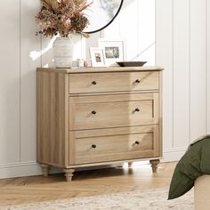 a wooden dresser with drawers and pictures on it's top shelf next to a bed