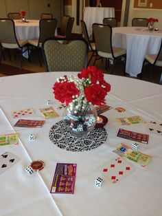 a table topped with cards and flowers on top of a white table cloth covered table