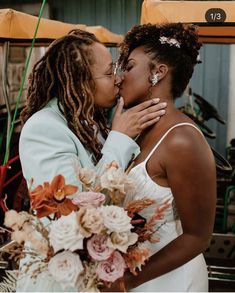 two women are kissing each other in front of a yellow vehicle with flowers on it