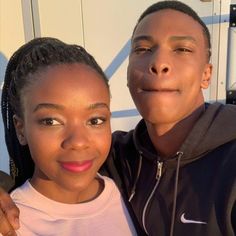 a man standing next to a woman in front of a white trailer with the sun shining on her face