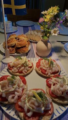 a table topped with mini sandwiches covered in toppings and shrimp on top of tomato slices