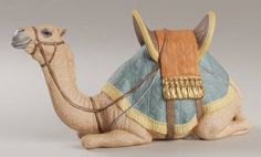 a ceramic figurine of a camel with a saddle on its back, sitting down