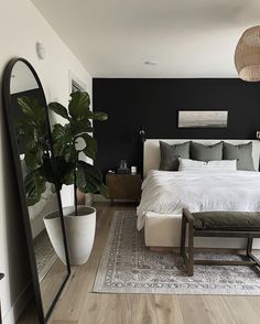 a bedroom with black walls, white bedding and wooden floors is pictured in this image