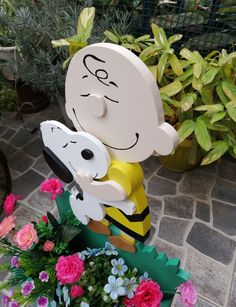 a statue of a person holding a dog on top of a planter filled with flowers