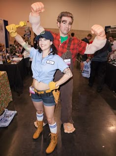 a man and woman dressed up in costumes at a convention or show, posing for the camera