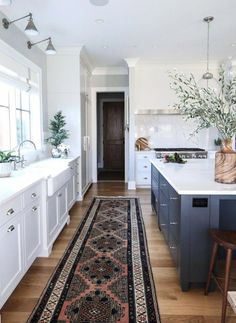 a large rug in the middle of a kitchen with blue cabinets and white counter tops