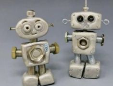 two metal robot figurines sitting next to each other