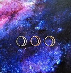 three rings sitting on top of a purple and blue surface with stars in the background