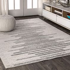 a white rug with grey lines on it in a living room next to a window