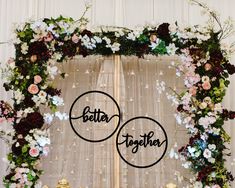 the letters better together are surrounded by flowers and greenery in front of a backdrop