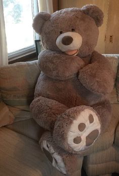 a large brown teddy bear sitting on top of a couch