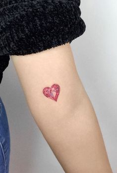 a woman's arm with a small heart tattoo on the left side of her arm