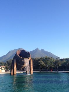 a large pipe sitting in the middle of a body of water with mountains in the background