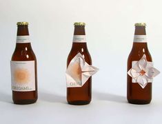 three beer bottles with origami on the top and bottom, one is brown