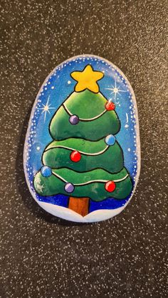 a painted rock with a christmas tree on it