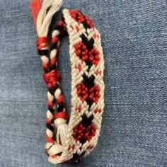 a close up of a bracelet on a person's lap with blue jeans behind it