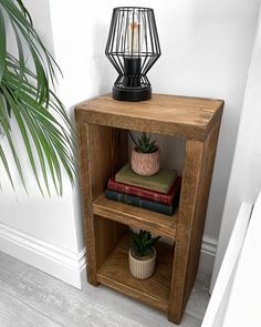 a wooden shelf with some books and a lamp on it next to a potted plant