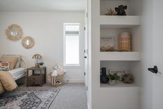 a bedroom with white walls and shelves filled with toys