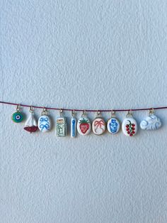 a string with charms hanging from it's sides on a white wall next to a red cord