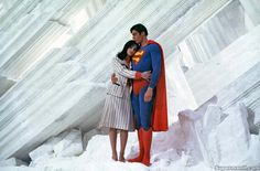 a man and woman dressed as superman standing in the snow with their arms around each other