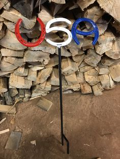 two olympic rings are on top of a pole in front of stacks of firewood