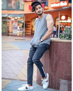 a man leaning against a wall with his hand on his hip