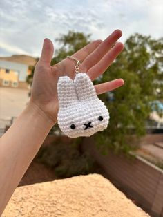 a hand holding a small crocheted keychain with a bunny face on it