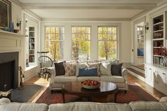 a living room filled with furniture and a fire place in front of a window covered in bookshelves