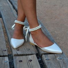 a close up of a person's feet wearing white shoes with pearls on them