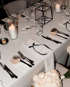 the table is set with white flowers and silverware, candles, and napkins