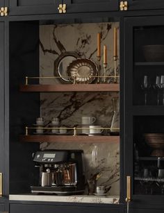 a kitchen with black cabinets and marble counter tops, gold trimming on the doors