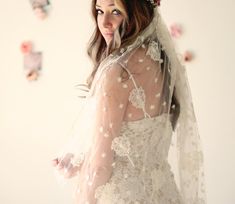 a woman in a wedding dress with a veil on her head is posing for the camera