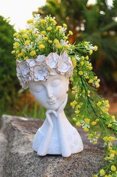 a white vase with flowers in it sitting on top of a rock