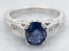 an oval shaped blue sapphire ring set in white gold with diamond accents on the band