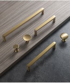 an assortment of brass handles and knobs on a gray surface with wood grained background