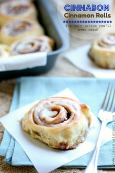 there is a cinnamon roll on a napkin with a fork next to it and two other pastries in the background