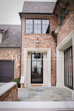 the front entrance of a brick house with black doors and windows on both sides of it