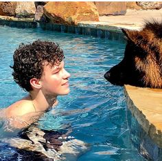 a boy and his dog are swimming in the pool