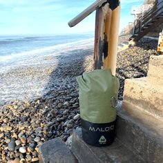 a bag is sitting on the steps by the water's edge, next to some rocks