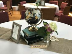 a globe sitting on top of a table next to some books and vases with flowers