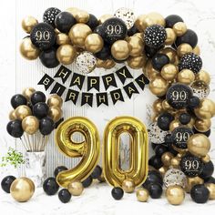 a 90th birthday decoration with balloons and streamers in black, gold and white colors