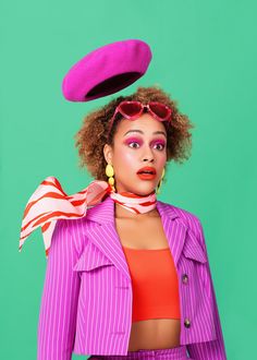 a woman with bright makeup wearing a pink suit and hat