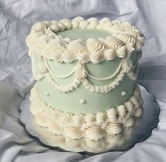 a three tiered cake with white icing on a sheet covered tablecloth,